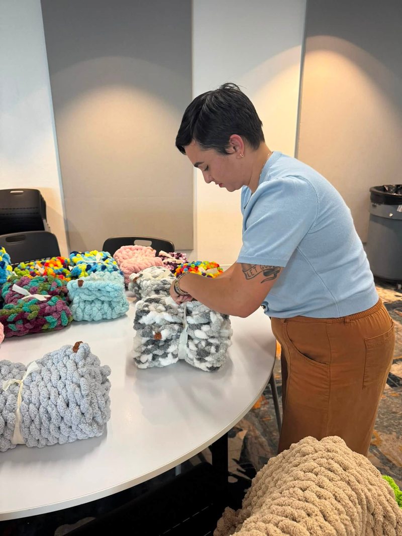 A person arranging handmade blankets at a gathering